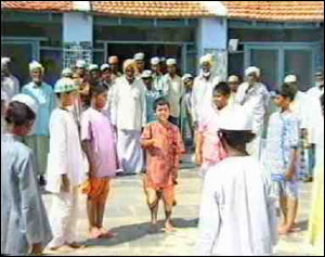 Young Sai is standing before a Mosque, surrounded by his friends. He is explaining the Hindu scriptures to them. 