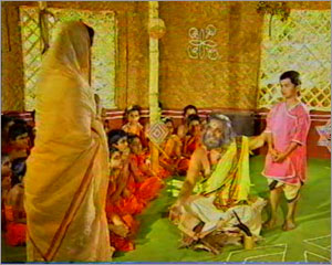Young Sai is standing before a Mosque, surrounded by his friends. He is explaining the Hindu scriptures to them. 